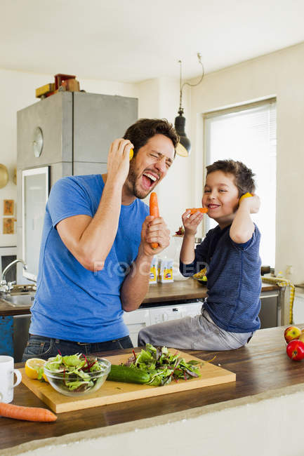 Padre e hijo pequeño cantando en micrófonos de zanahoria - foto de stock