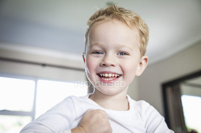 Портрет улыбающегося дошкольника, смотрящего в камеру в помещении — стоковое фото