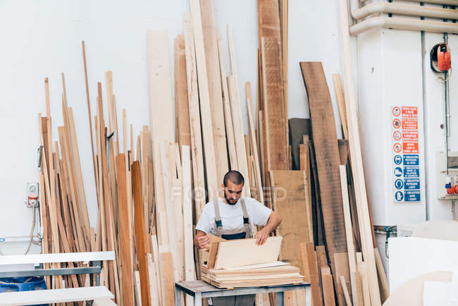Carpintero seleccionando madera en taller - foto de stock