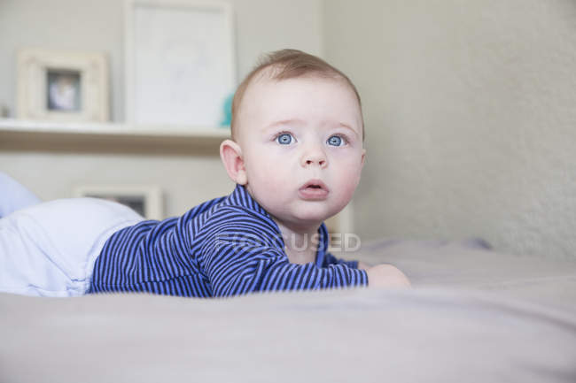 Ritratto di bambino dagli occhi azzurri sdraiato sul letto — Foto stock