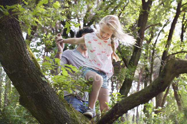 Father helping daughter to climb tree — Stock Photo