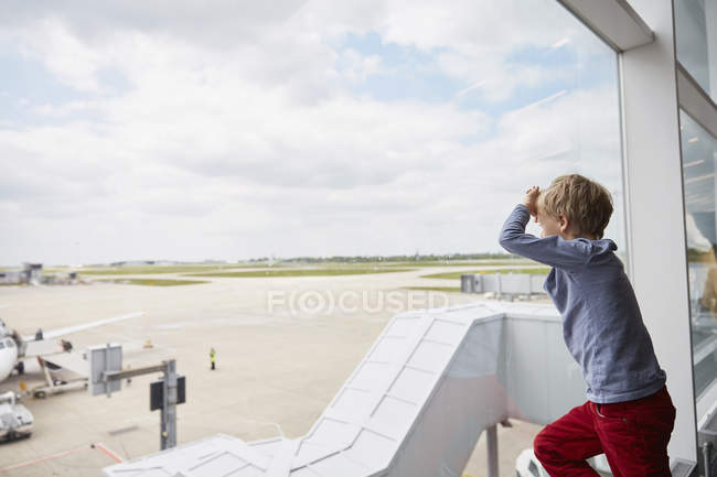Ragazzo che guarda fuori dalla finestra dell'aeroporto sulla pista, Londra, Regno Unito — Foto stock