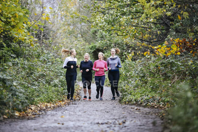 Adolescente chica y mujeres corredores corriendo en el parque - foto de stock