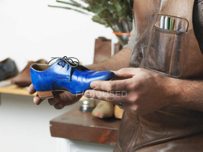 Чоботар, тримаючись за синій черевичок семінар — стокове фото