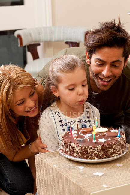 Parents and child blowing out candles — Stock Photo