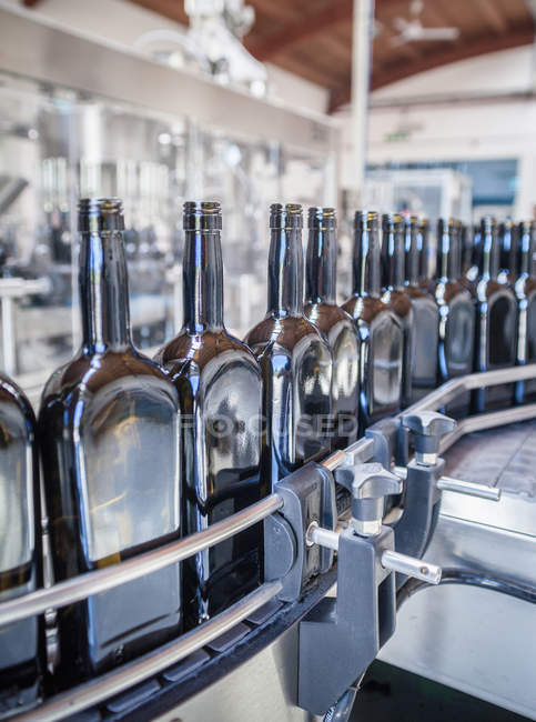 Filas de botellas en línea de producción en fábrica - foto de stock