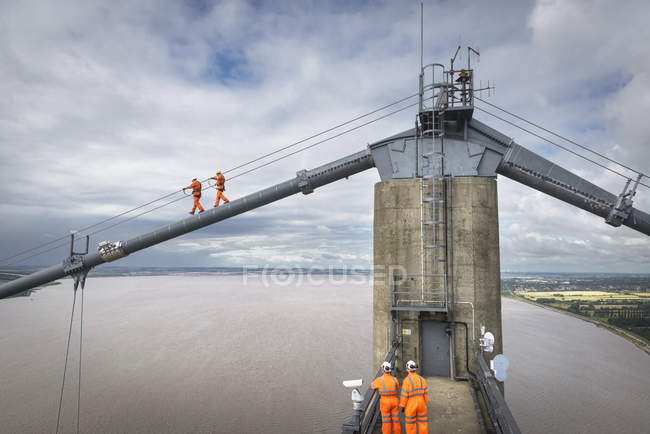 Trabajadores de puentes caminando sobre cables de puente colgante, Humber Bridge, Reino Unido - foto de stock