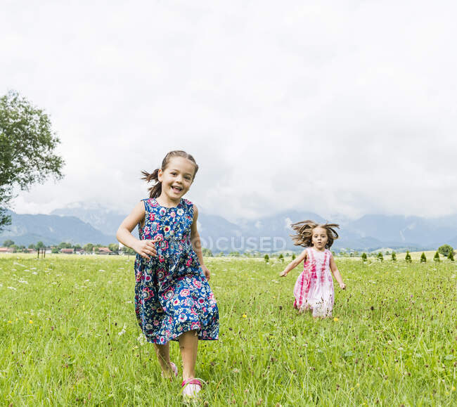 Girls running in field, Fuessen, Bavaria, Germany — Stock Photo