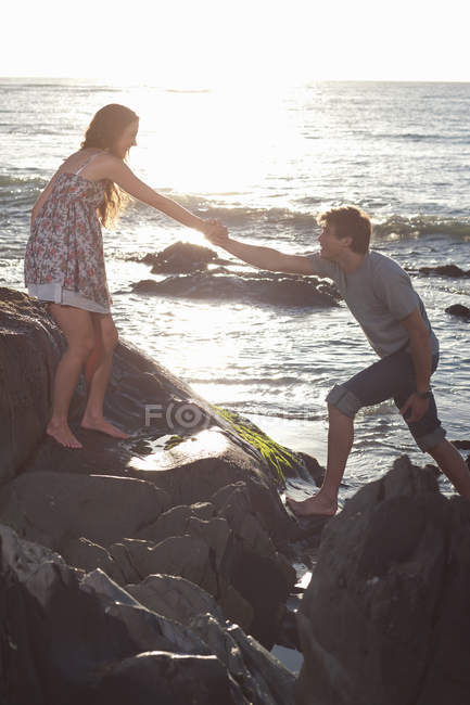 Couple escalade rochers sur la plage — Photo de stock