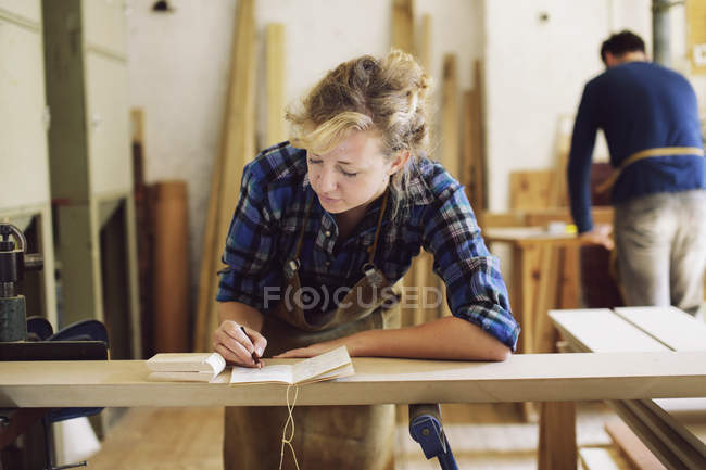Young craftswoman making notes in pipe organ workshop — Stock Photo