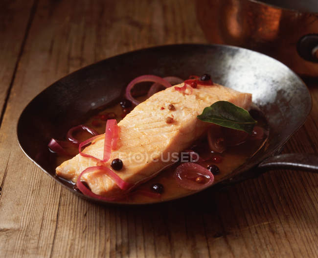 Salmon with red onion and juniper in frying pan — Stock Photo