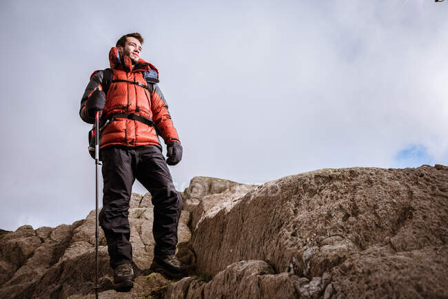 Jovem caminhante do sexo masculino olhando para fora das rochas, The Lake District, Cumbria, Reino Unido — Fotografia de Stock