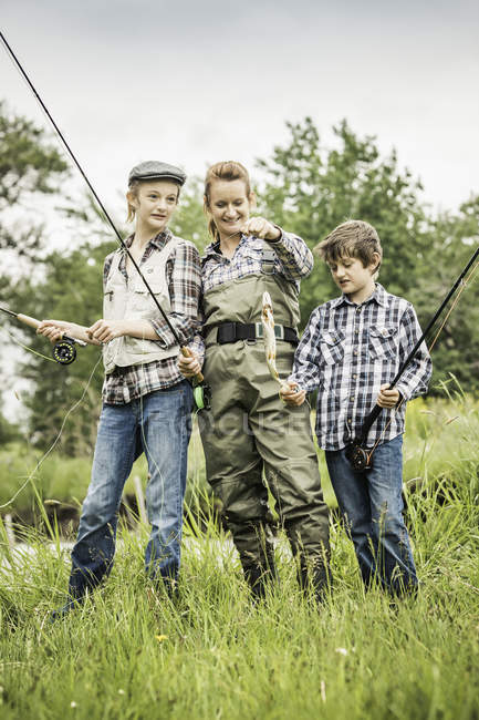 Mother and children standing holding freshly caught fish — Stock Photo