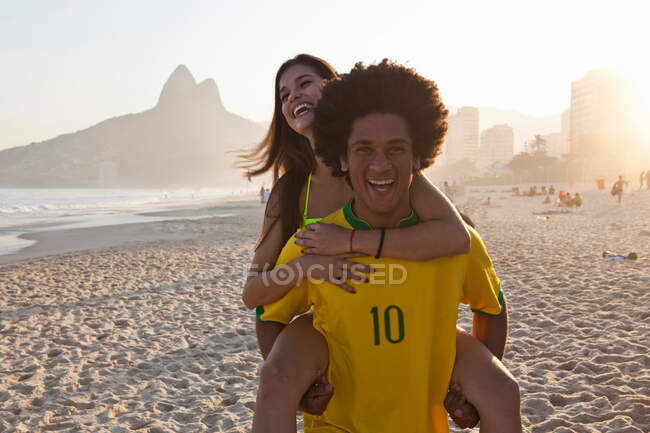 Giovane uomo che dà fidanzata a cavalluccio, Ipanema Beach, Rio, Brasile — Foto stock