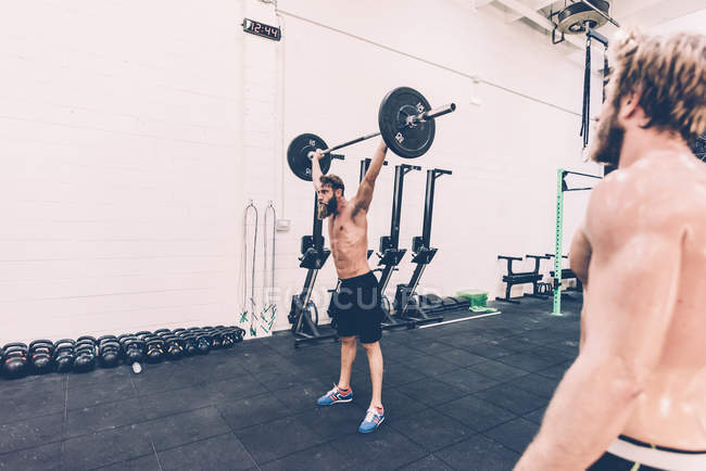 Jeune homme cross trainer arracher haltère de levage dans la salle de gym — Photo de stock