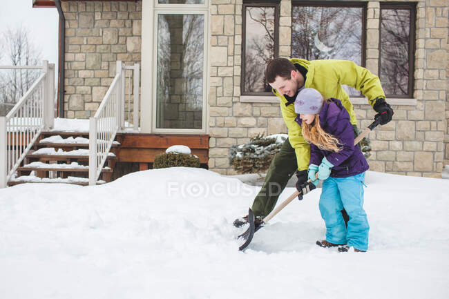 Отец помогает дочери убирать снег. — стоковое фото
