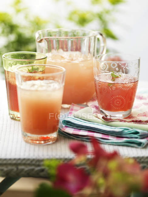 Glasses of fresh home made fruit drinks and ice — Stock Photo