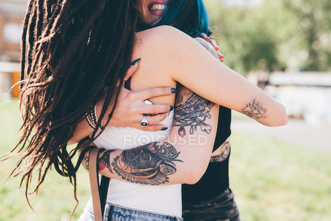 Tattooed young women hugging in urban park — smiling, cool - Stock Photo |  #167860168