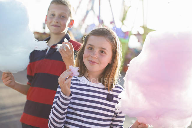 Brother and sister eating pink candyfloss at fairground — Stock Photo