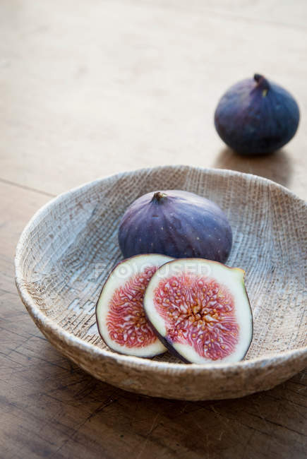 Fresh halved and whole figs in wooden bowl — Stock Photo