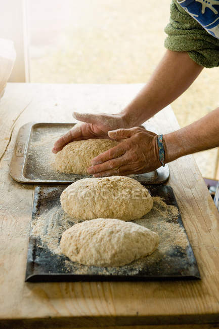 Cropped image of man cooking loafs of bread — Stock Photo