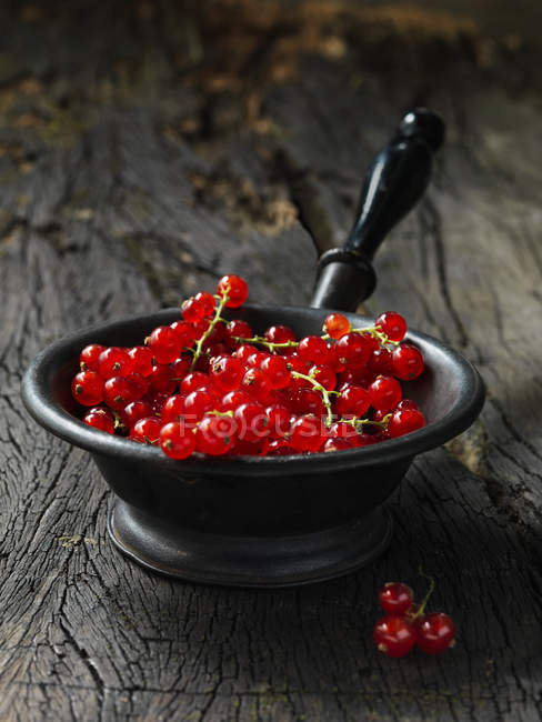 Ribes rosso in piccolo setaccio metallico vintage, tavolo in legno rustico — Foto stock