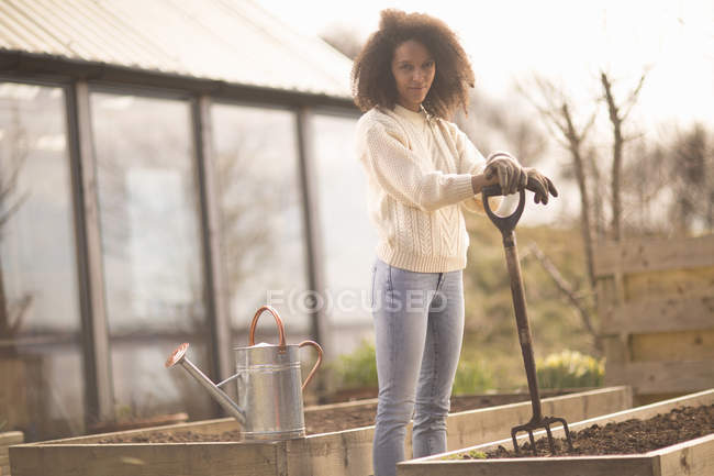 Mid adult woman by raised bed with garden fork, portrait — Stock Photo