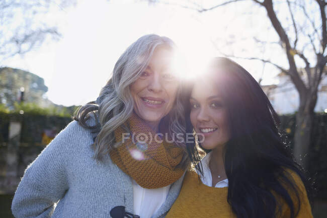 Women in garden arms around each other looking at camera smiling — Stock Photo