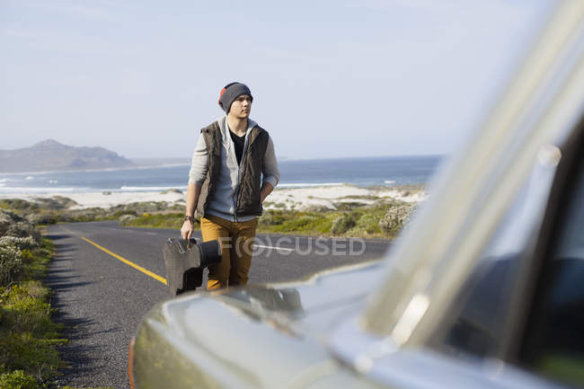 Young man behind parked car with guitar case, Cape Town, Western Cape, South Africa — Stock Photo