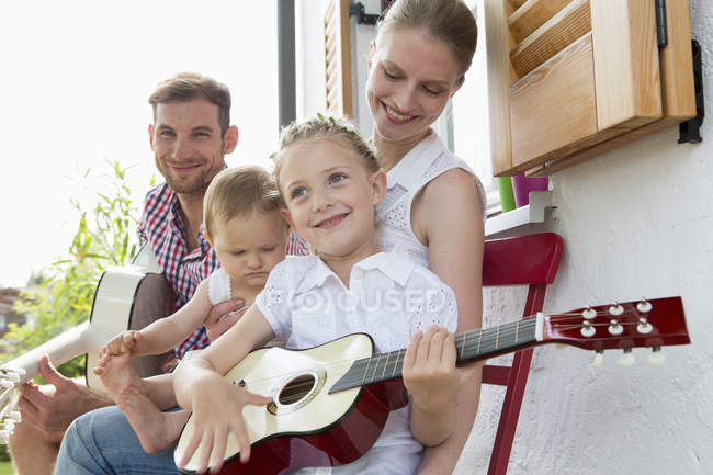 Ragazza che suona la chitarra con la famiglia — Foto stock