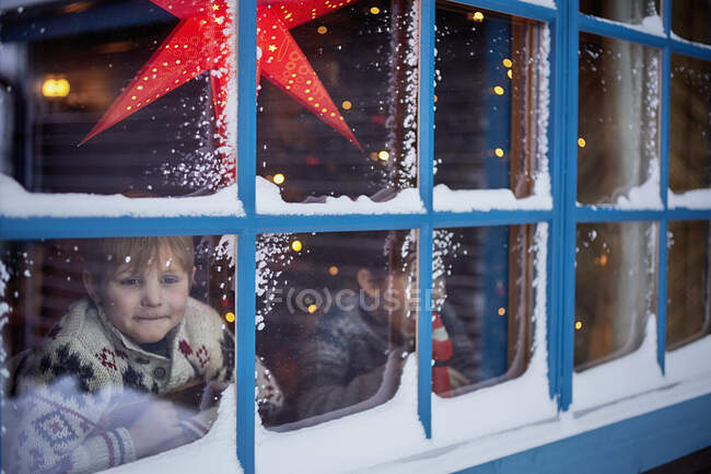 Two brothers looking out of cabin window at Christmas — Stock Photo