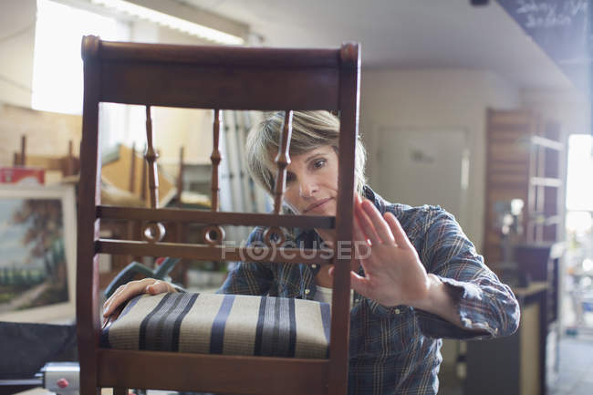 Frau in Werkstatt untersucht Stuhl — Stockfoto
