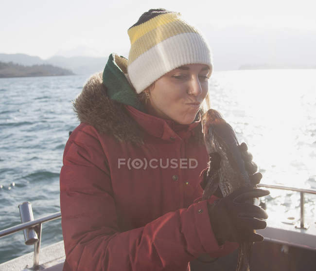 Mujer joven sosteniendo pescado en barco - foto de stock