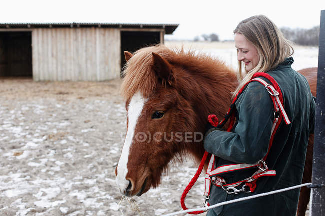 Mujer sonriendo con caballo en el patio - foto de stock