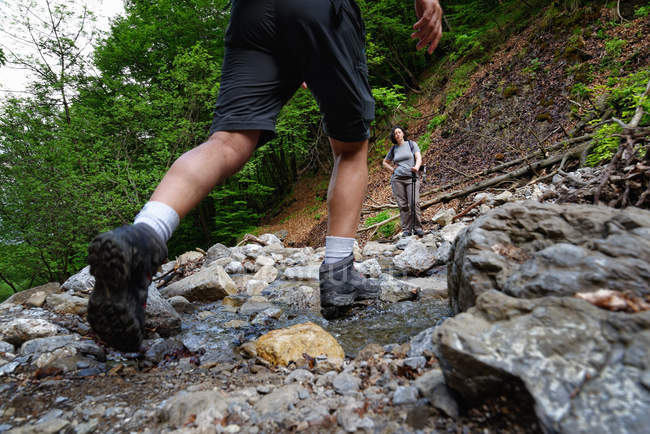 Waist down rear view of mature male hiker hiking in stream — Stock Photo