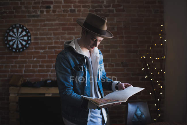 Young man at home, reading magazine — Stock Photo