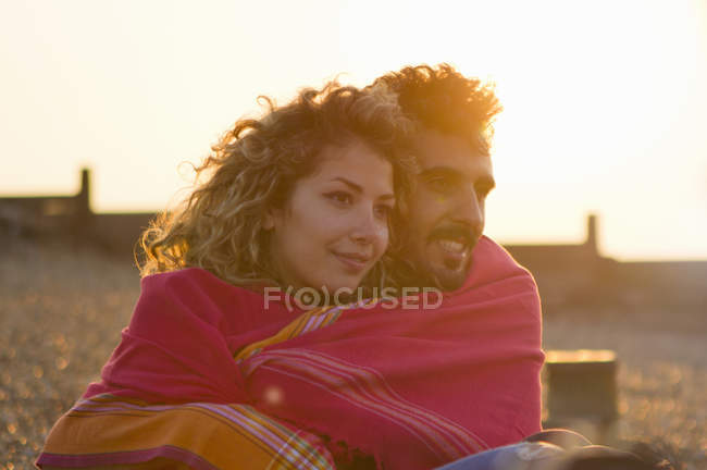 Casal jovem envolto em toalha na praia — Fotografia de Stock