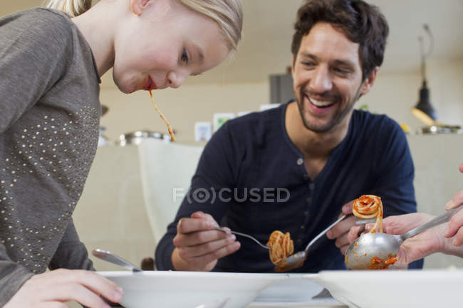 Mid adult man and daughter eating a spaghetti meal — Stock Photo