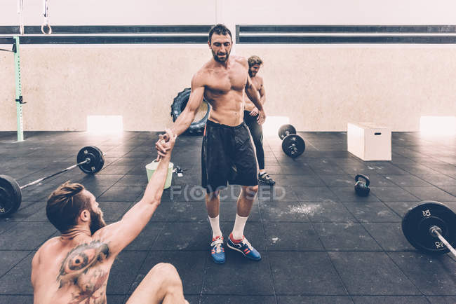 Male cross trainer taking a water break from weightlifting in gym — Stock Photo