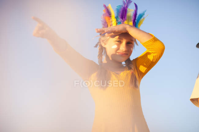 Ragazza vestita da nativa americana in copricapo di piume con occhi ombreggiati a mano che puntano — Foto stock