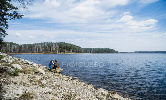 Dos amigas senderistas tomando un descanso en la orilla del lago - foto de stock