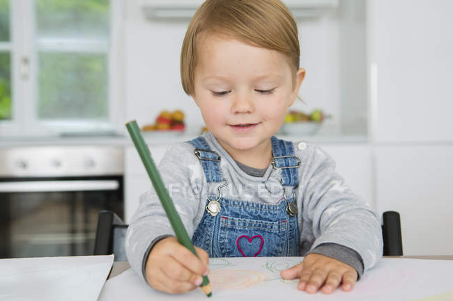 Female toddler drawing at kitchen table — Stock Photo