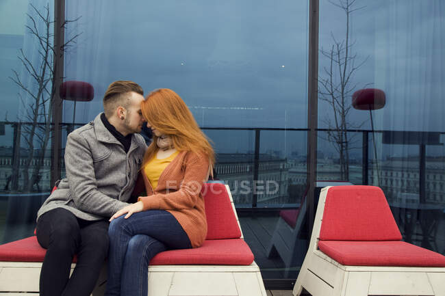 Romántica pareja joven sentada al aire libre en la terraza de la azotea - foto de stock