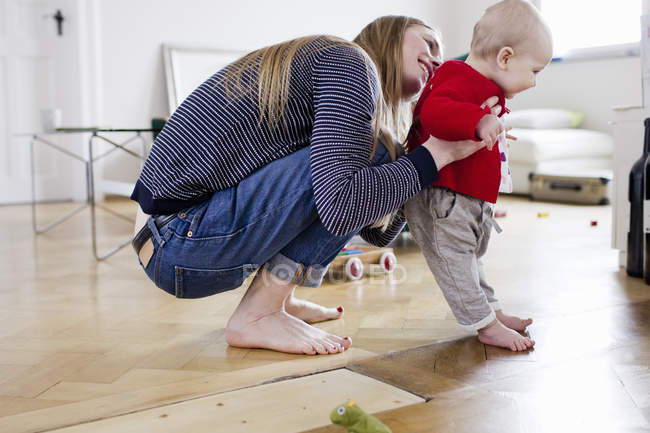 Взрослая женщина держит маленькую дочь, чтобы сделать первые шаги — стоковое фото