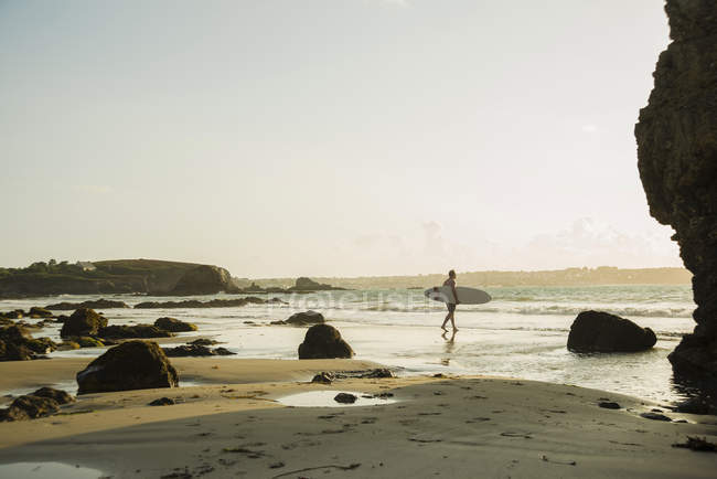 Homem maduro caminhando em direção ao mar, segurando prancha de surf — Fotografia de Stock