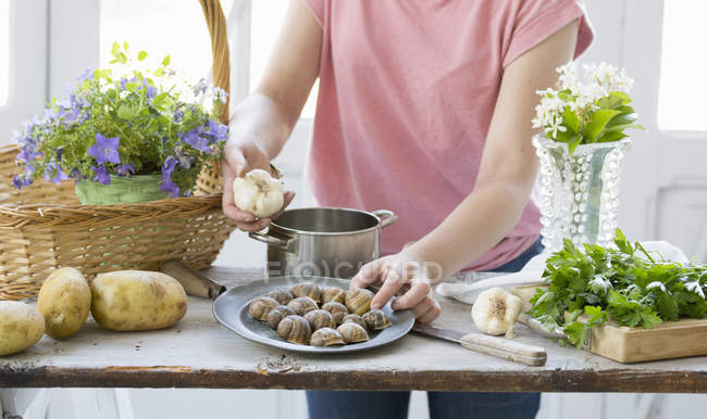 Молода жінка готує равликів і часник в кухонного столу, місті Vogogna, Verbania, -П'ємонте, Італія — стокове фото