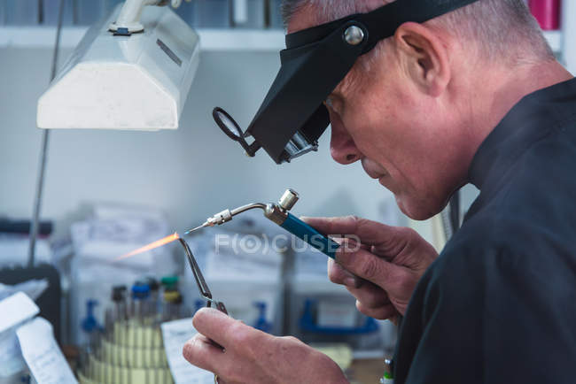 Male jewelry craftsman using miniature blowtorch on platinum ring — Stock Photo