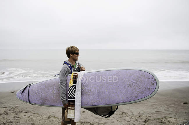 Joven surfista masculino en la playa brumosa, Bolinas, California, EE.UU. - foto de stock