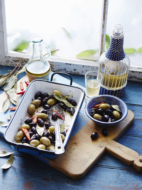 Aceitunas tibias y botella de aceite de oliva en el alféizar de la ventana - foto de stock