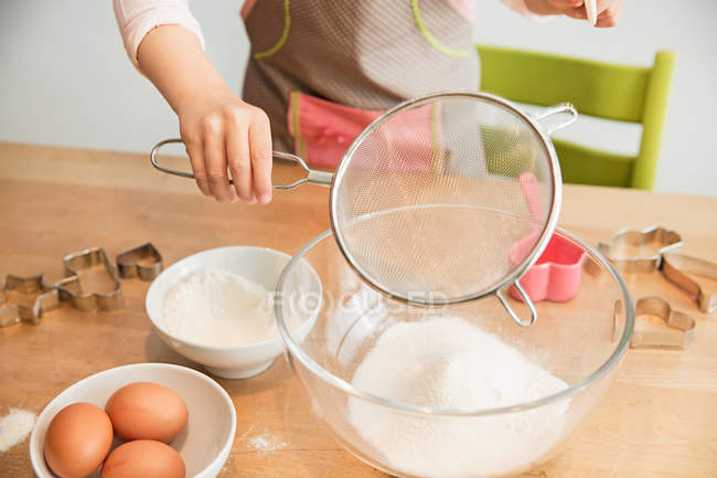 Fille tamiser la farine dans un bol de mélange — Photo de stock